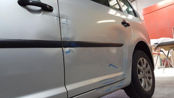 Door and wing damage on a silver car before repair